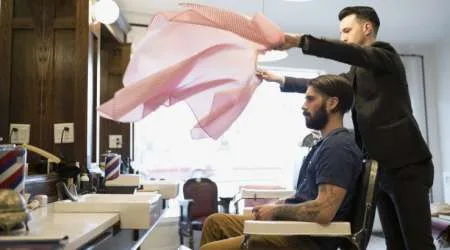 Barber flipping smock over customer in barber shop