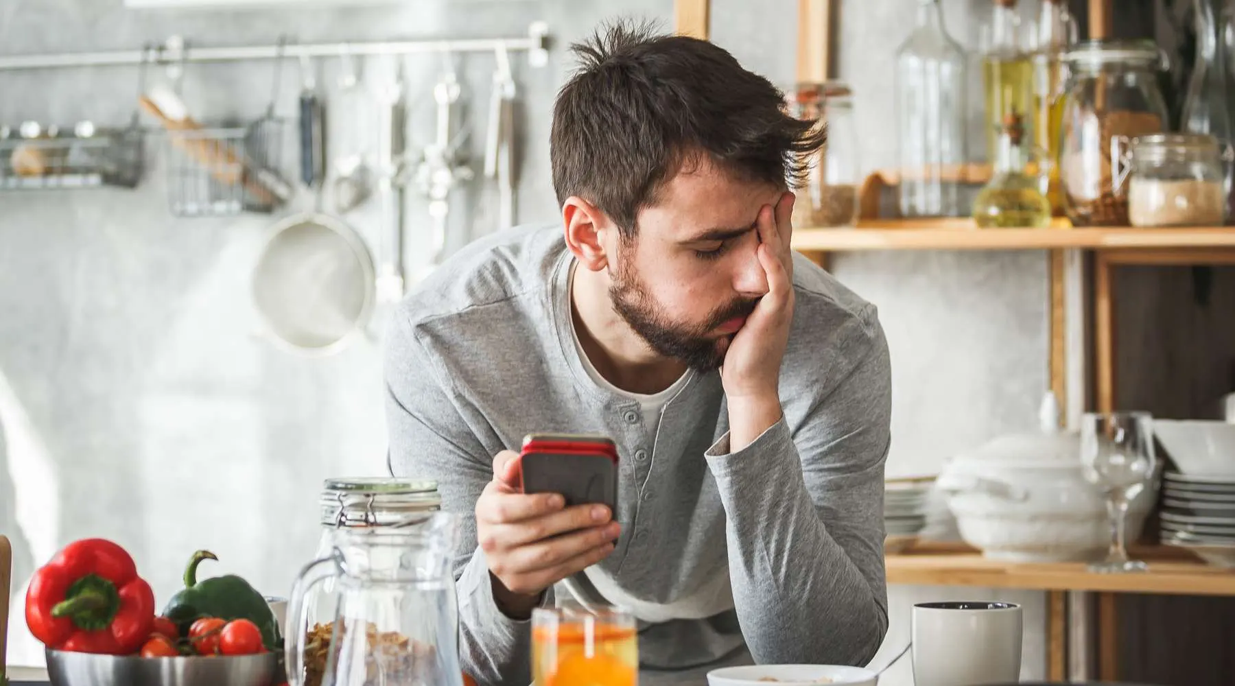 Sad man using smart phone during breakfast at home