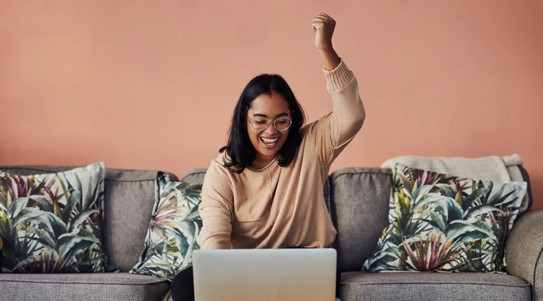 A woman celebrates a victory on her laptop.