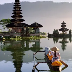 Woman in a traditional Indonesian boat facing a temple in Bali.