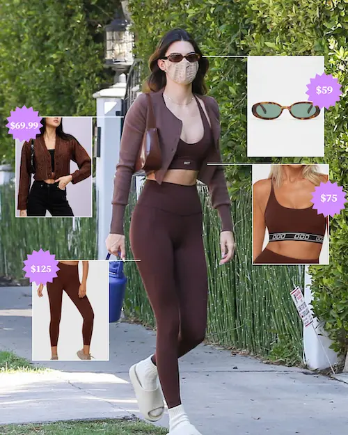 Kendall Jenner wearing chocolate brown leggings, sports bra and cardigan with cream slides and oval sunglasses.