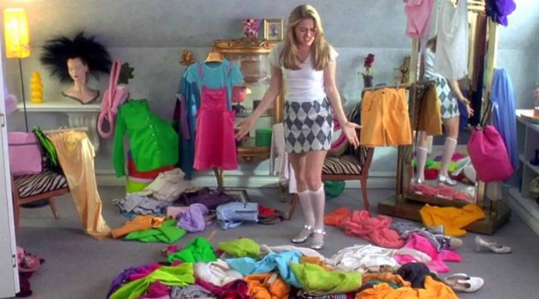 Cher Horowitz de Clueless debout avec une pile de vêtements sur son sol. 
