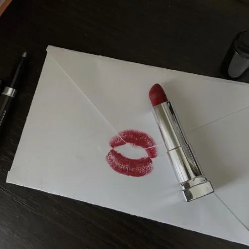 Image of a lipstick kiss print on a white envelope next to a lipstick