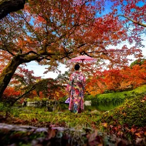 woman in floral kimono standing in an autumn garden
