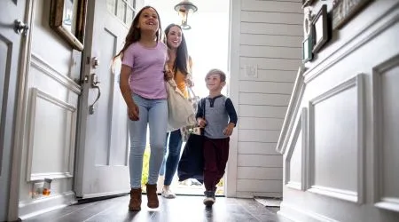 A mother and two kids running into their new home together 