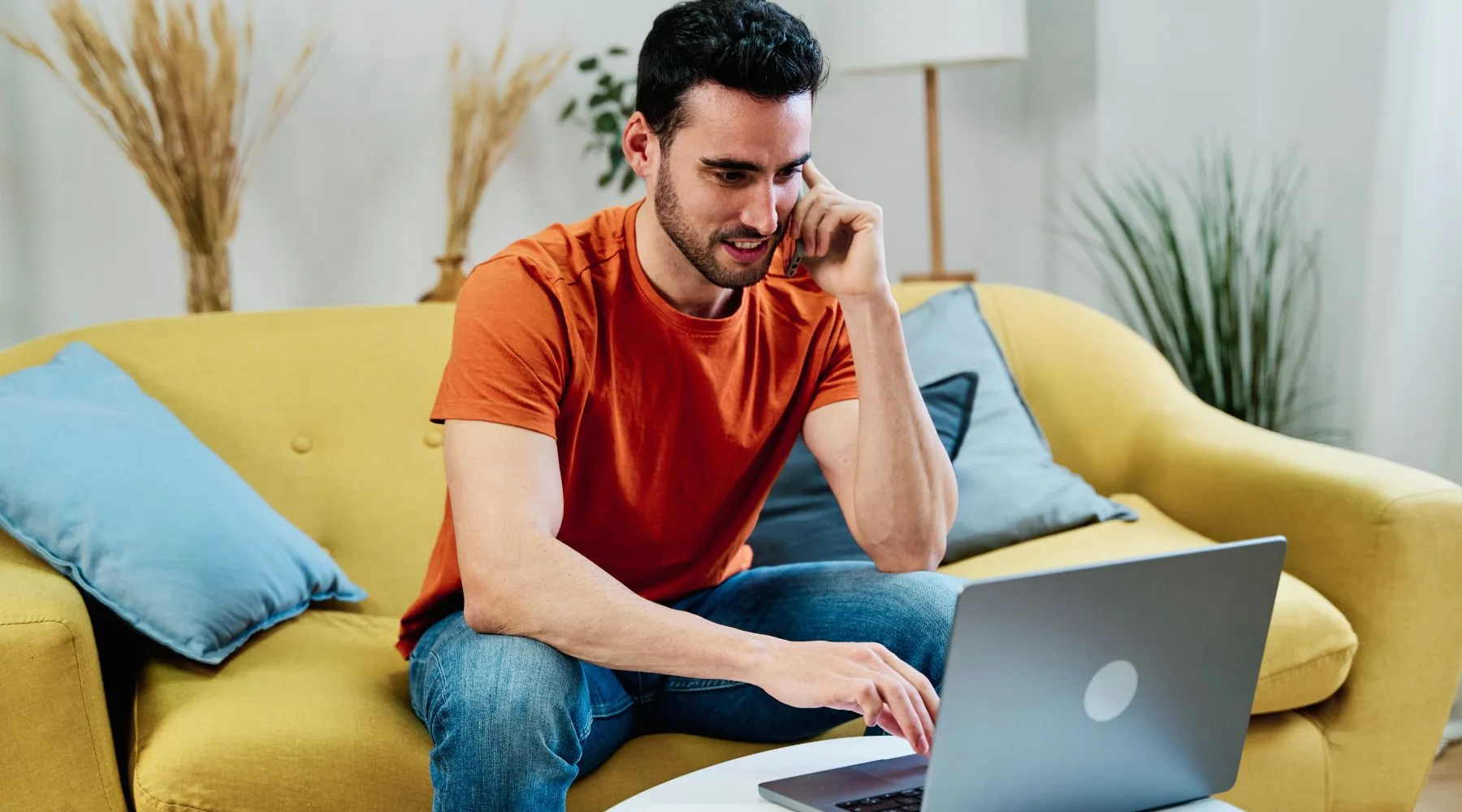 Man_Trading_On_Laptop_Phone_From_Couch_Canva_1800x1000 Man_Trading_On_Laptop_Phone_From_Couch_Canva_1800x1000