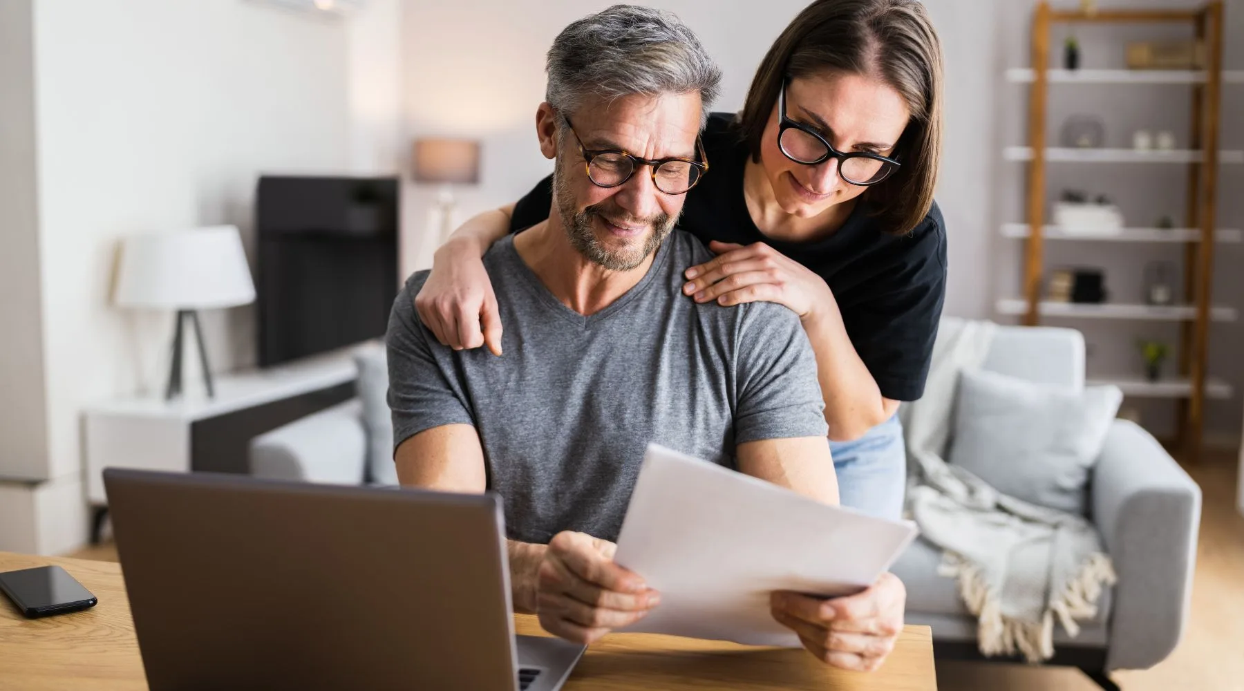 Couple_Reviewing_Account_Details_On_Paper_And_Laptop_Canva_1800x1000