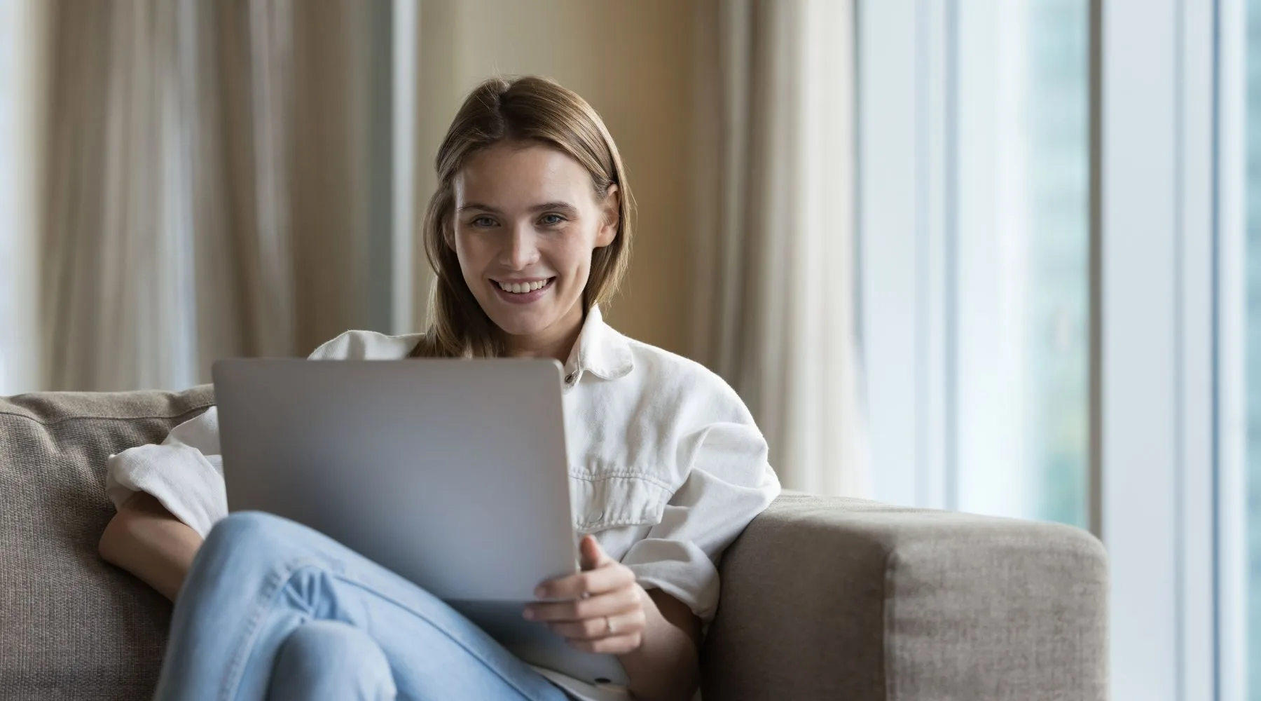 Happy_Woman_On_Laptop_Sitting_On_Couch_Canva_1800x1000