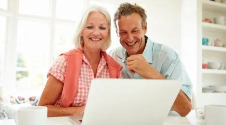 A middle-aged couple reviewing their superannuation on a laptop together