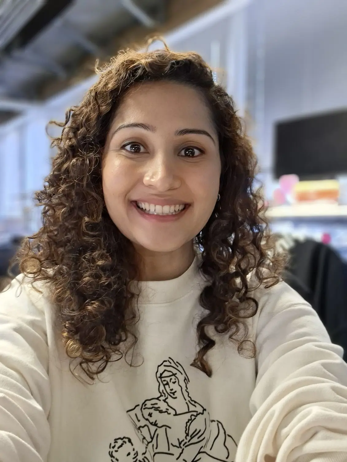 A smiling woman wearing a white sweatshirt image taken using the Samsung Galaxy A57.
