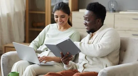 A couple on the lounge together, looking at a laptop. 