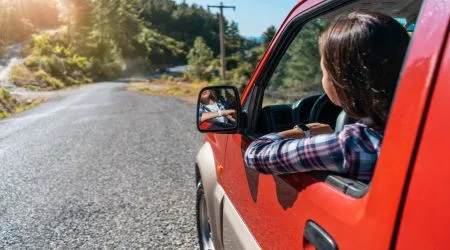 Woman leaning out of a red car's window.