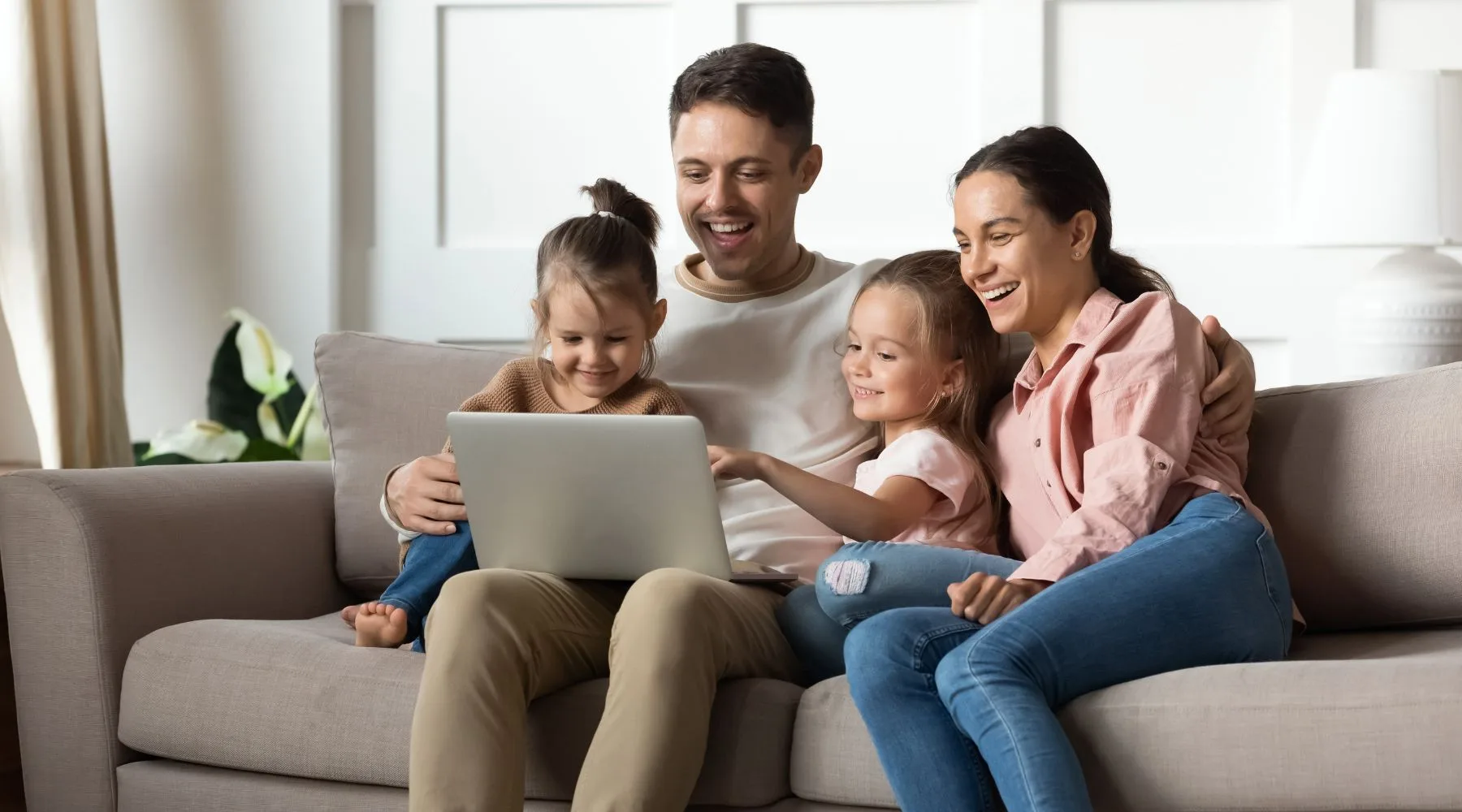 Happy_Family_On_Laptop_together_Living_Room_Canva_1800x1000 Happy_Family_On_Laptop_together_Living_Room_Canva_1800x1000