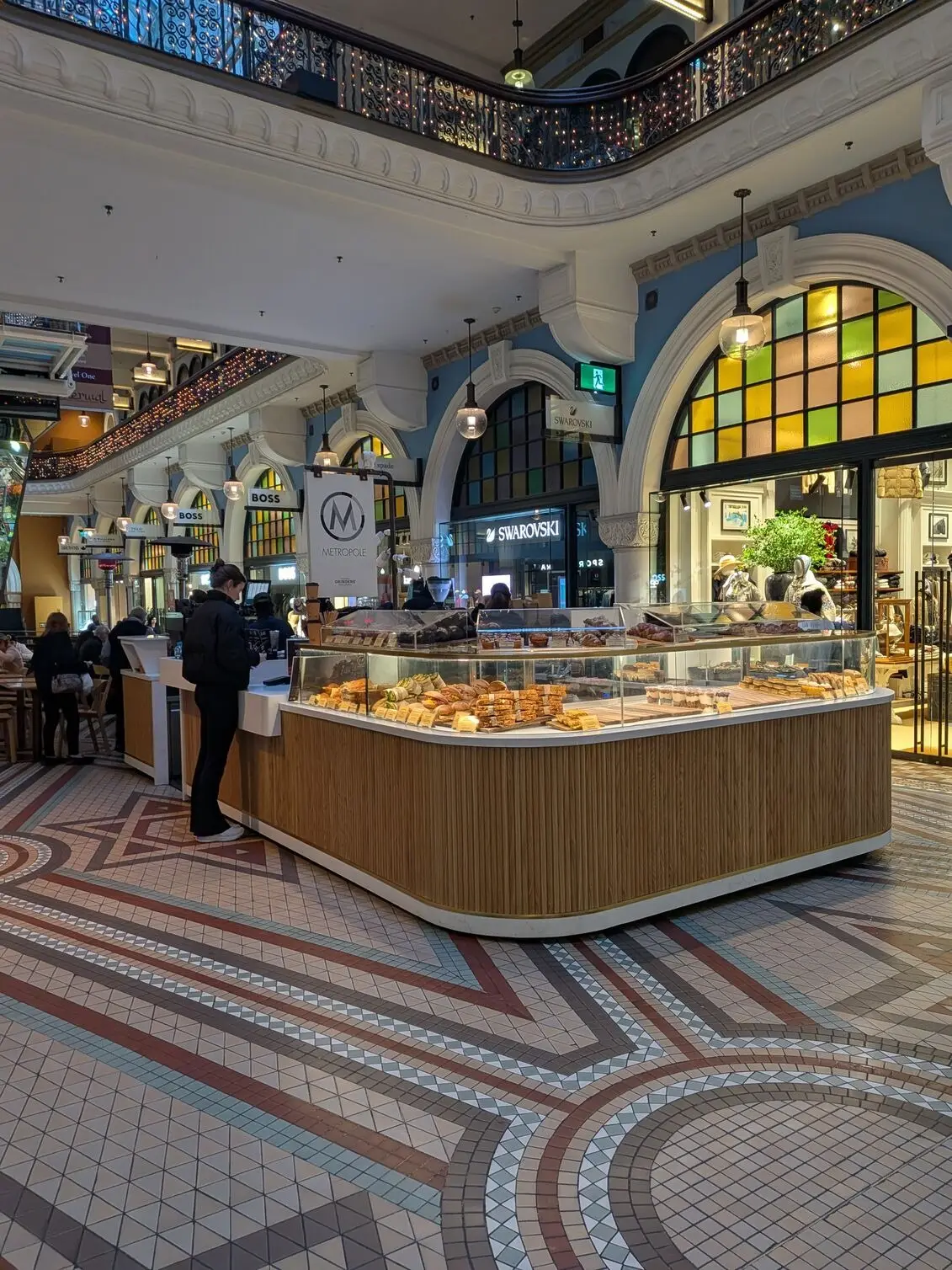 Google Pixel 10a showcases the warm architectural details and stained-glass windows of a café counter inside the mall.