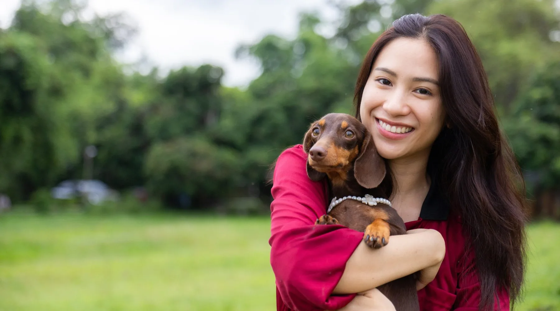 Happy_Woman_Holding_Dog_In_Park_Canva_1800x1000 Happy_Woman_Holding_Dog_In_Park_Canva_1800x1000