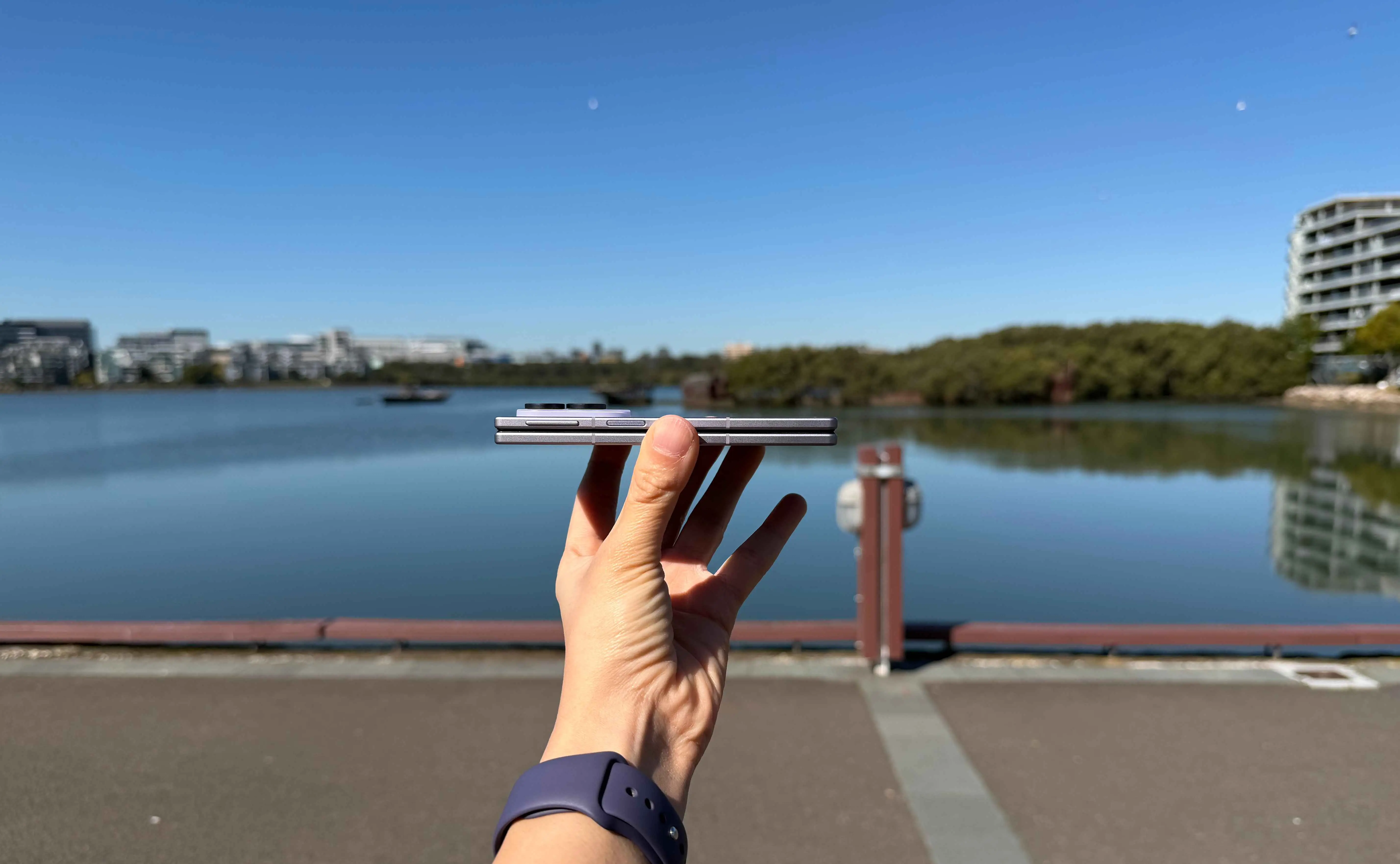 A side profile view of the Samsung Galaxy Z Fold 8, highlighting its slim hinge line and slab-like thickness against a lakeside backdrop.