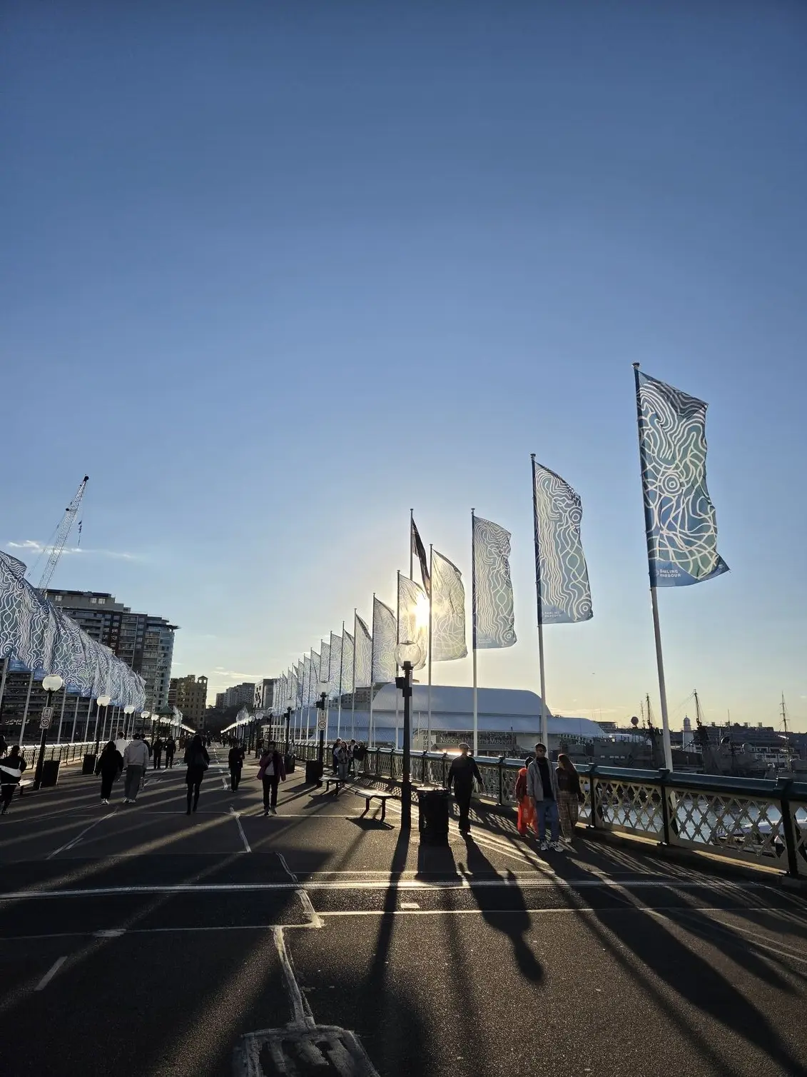 A backlit harbourside boardwalk shot from the Samsung Galaxy Z Fold 8, testing its dynamic range against strong sun flare and long shadows. 