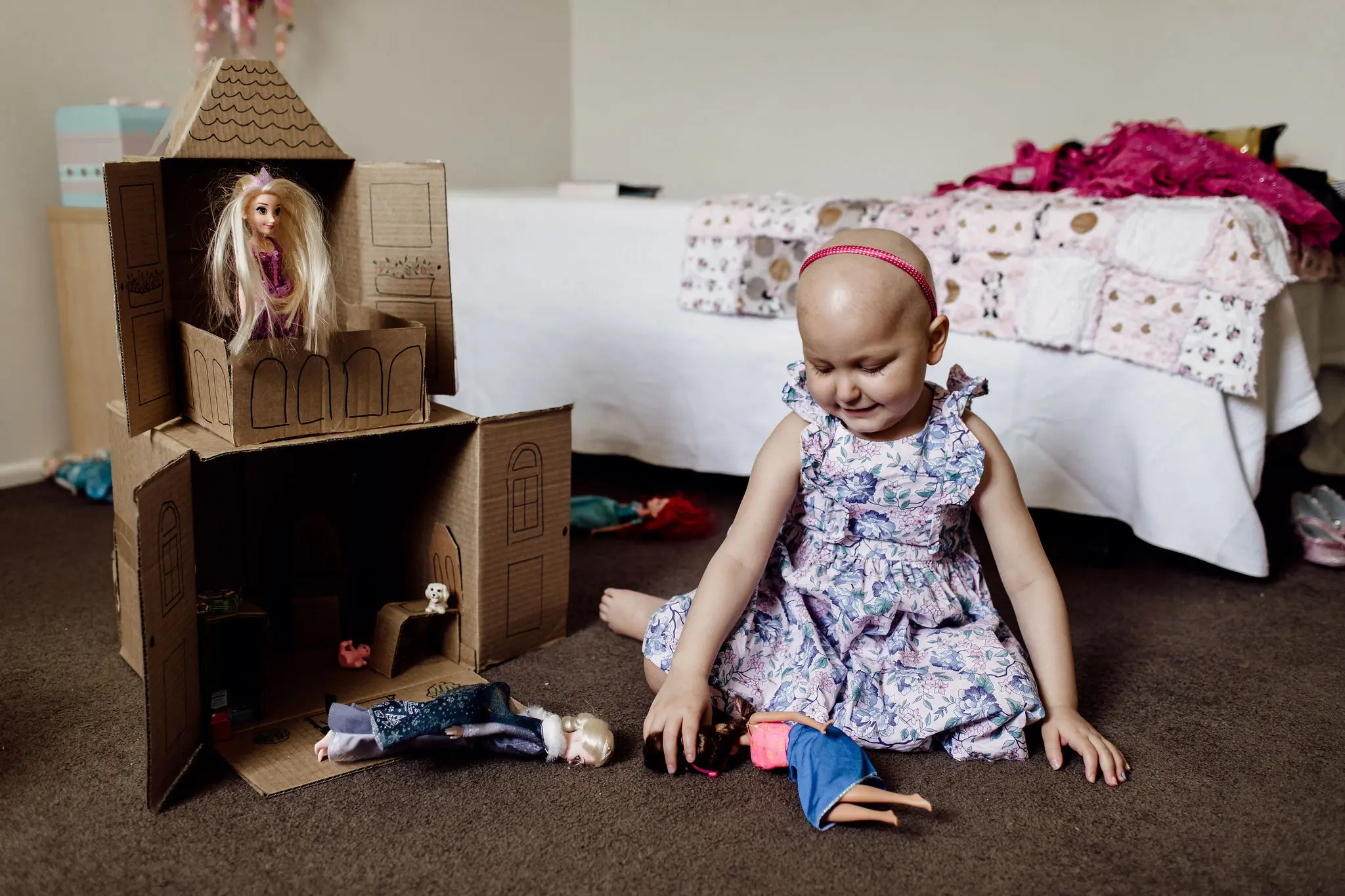 A child playing with a cardboard dollhouse